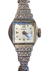 Close-up of 14K white gold Art Deco Benrus watch showing five-tier stepped diamond-set shoulders inspired by skyscraper design.