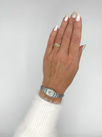 Hand wearing 1928 Bulova Art Deco ladies watch in 14K white gold with diamonds and emeralds on a plain background