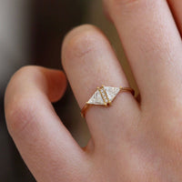 Artemer 18k gold triangle diamond engagement ring worn on finger.
