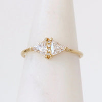 Gold ring with triangular diamond design on a white background