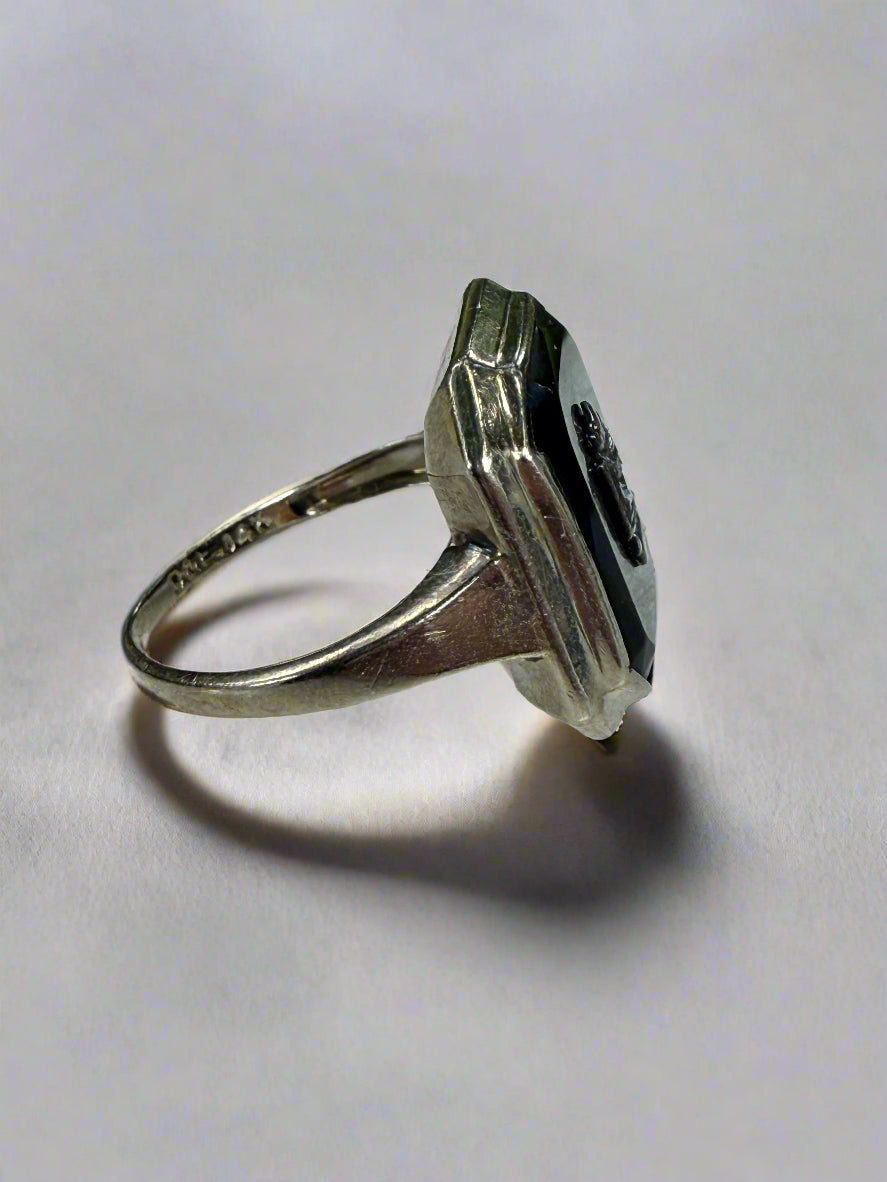 Side view of a white gold ring with a black stone on a white surface