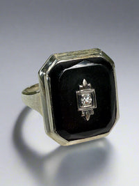 White gold, onyx and diamond ring on a white surface