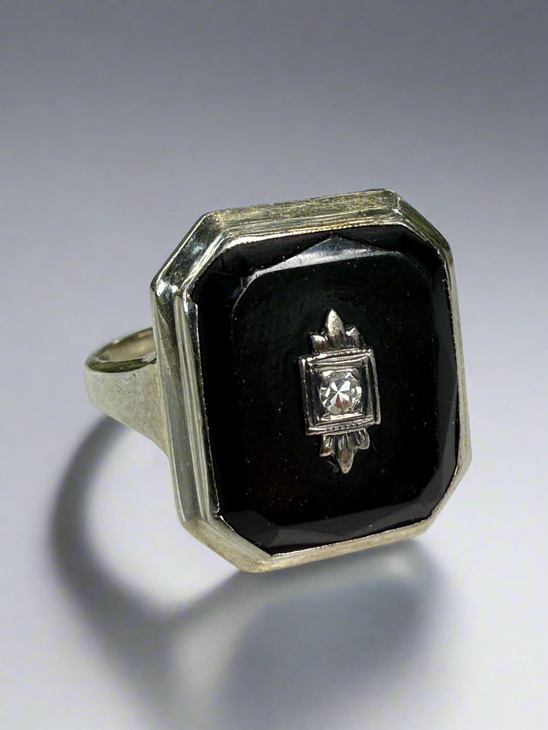 White gold, onyx and diamond ring on a white surface