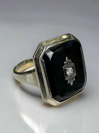 Ring with black gemstone and diamond on a white surface