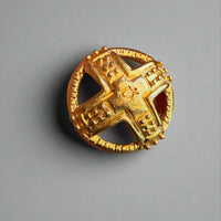 Gold decorative button held in a hand with a blurred background