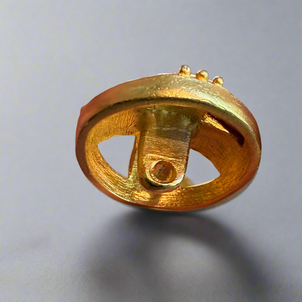 Gold decorative button held between fingers with more buttons in the background.
