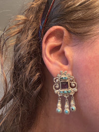 Close-up of an ear wearing Matl decorative silver earring with turquoise stones.
