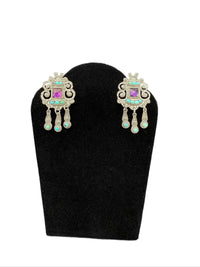 Pair of ornate Matl 925 amethyst and turquoise earrings on a black stand with a white background