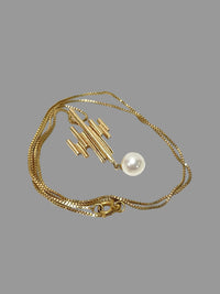 1960s modernist gold pendant necklace featuring geometric bars and a single pearl drop.