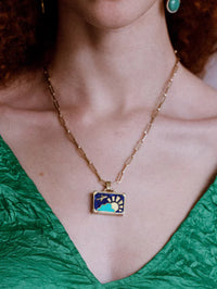 NeverNot Dreamy Night pendant showing lapis sky, turquoise cloud, gold airplane, and mother of pearl accents won on model.