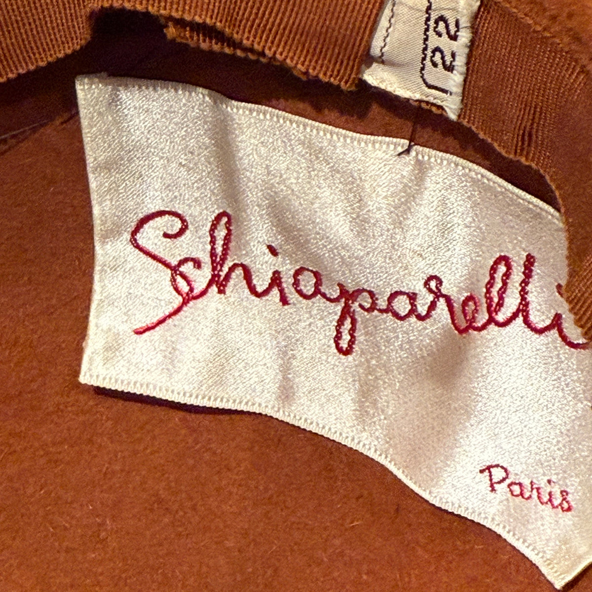 Label close-up of 1950s Schiaparelli Paris cocktail hat with sculptural feather adornment