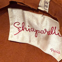 Label close-up of 1950s Schiaparelli Paris cocktail hat with sculptural feather adornment